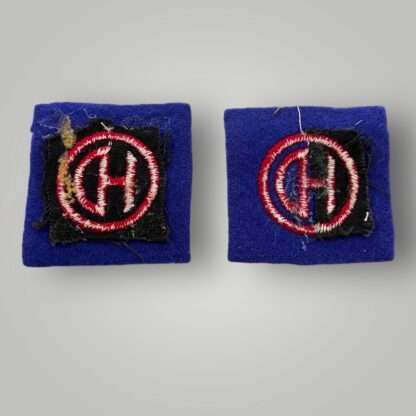 Reverse image of a set of British WW2 51st Highland Division formation badges, machine embroiderd depicting the letters HD conjoined in red within a red circle on a blue woollen backing.