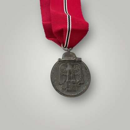 Eastern Front Medal, constructed in zinc with nice long ribbon. The suspension ring is stamped with PZK code “55” for J.E. Hammer & Söhne.