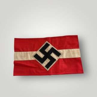 An original Hitler Youth cloth armband, two part construction in red cotton overlaid by a white cotton diamond bearing a black swastika.