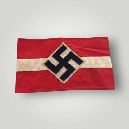 An original Hitler Youth cloth armband, two part construction in red cotton overlaid by a white cotton diamond bearing a black swastika.