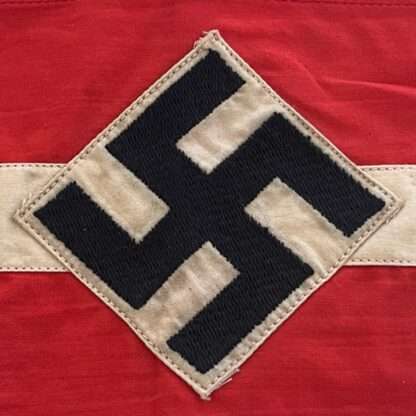 An original Hitler Youth cloth armband, two part construction in red cotton overlaid by a white cotton diamond bearing a black swastika.