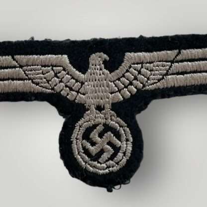 An M38 (Heer) Embroidered Breast Eagle, machine embroidered in silver grey thread on green woollen backing.