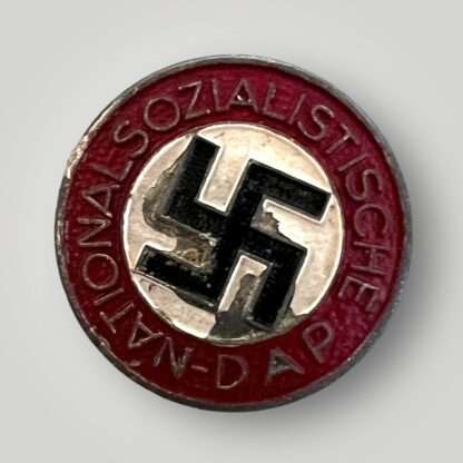 An NSDAP Party pin late war painted badge depicts a roundal with the inscription 'D.A.P. National-Sozialistische' with a painted black swastika in the centre with a white background.