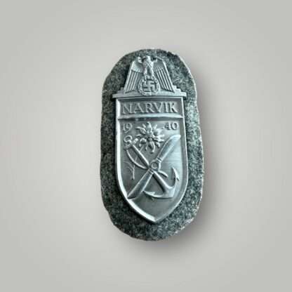 An Heer (Army) Narvik campaign shield by Deumer, constructed in zinc on field grey woollen backing.