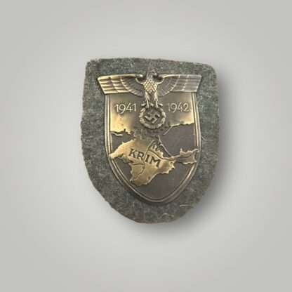 An original Heer Krim Campaign Shield magnetic version with bronze finish with beautiful patina, mounted on field-grey woolen background.