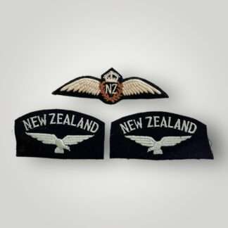 An original WW2 Royal New Zealand Air Force pilot wings & set of shoulder titles. The obverse of the pilot wings are machine embroidered with  outstretched wings supporting a central laurel wreath with the 'NF' monogram in the centre for New Zealand surmounted by King's crown.