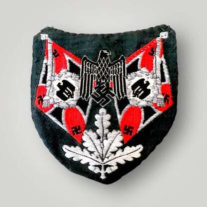 An original Heer Artillery Flag Bearers Sleeve Badge, flat Bevo weave construction in red, black, and aluminium thread on green rayon backing.