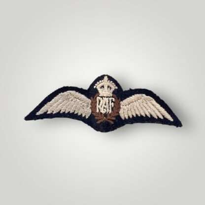 A British WW2 Royal Air Force pilot wings, machine embroidered. The insignia depicts a central laurel wreath that encircles the 'RAF' monogram is stiched in light brown thread which is surmounted by the Kings crown with outstretched wings either side.