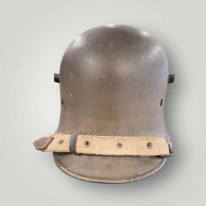 A German/Austrian M16 steel helmet from WW1. The helmet retains its original factory green paint finish complete with canvas strap.