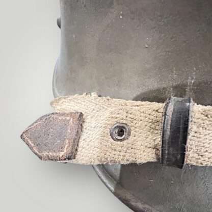 A German/Austrian M16 steel helmet from WW1. The helmet retains its original factory green paint finish and has a canvas strap.