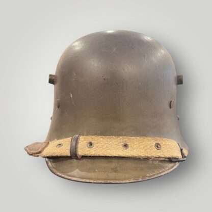 A German/Austrian M16 steel helmet from WW1. The helmet retains its original factory green paint finish with canvas chin strap.