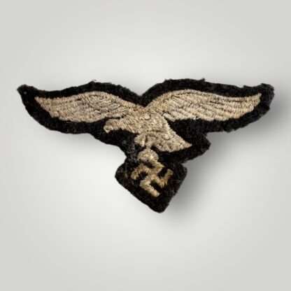 Reverse image of a WW2 German Luftwaffe EM/NCOs visor cap eagle, machine embroidered in silver thread on blue woollen backing.