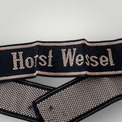 A 18th SS Volunteer Panzergrenadier Division Horst Wessel cufftitle. The insignia is constructed from woven black rayon, with the obverse side trimmed at both the top and bottom with machine-embroidered silver-grey tresses.
