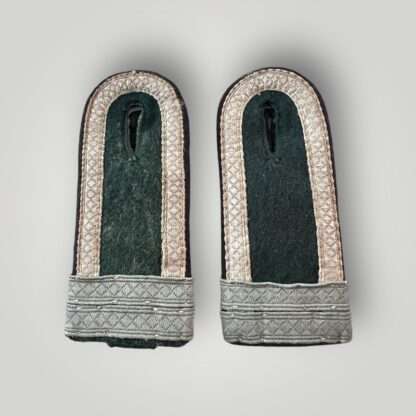 A matching pair of Heer M44 Pioneer Fahnenjunker Unteroffizier shoulder boards, constructed on dark green wool with diamond patterned matt blue/grey tress on the outer edge, with two horizontal tress strips denothing the rank of Fahnenjunker Unteroffizier with black rayon waffenfarbe piping for pionner troops
