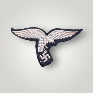 An early Luftwaffe breast eagle 'drop tail' version, machine embroidered with white thread on blue-grey wool.