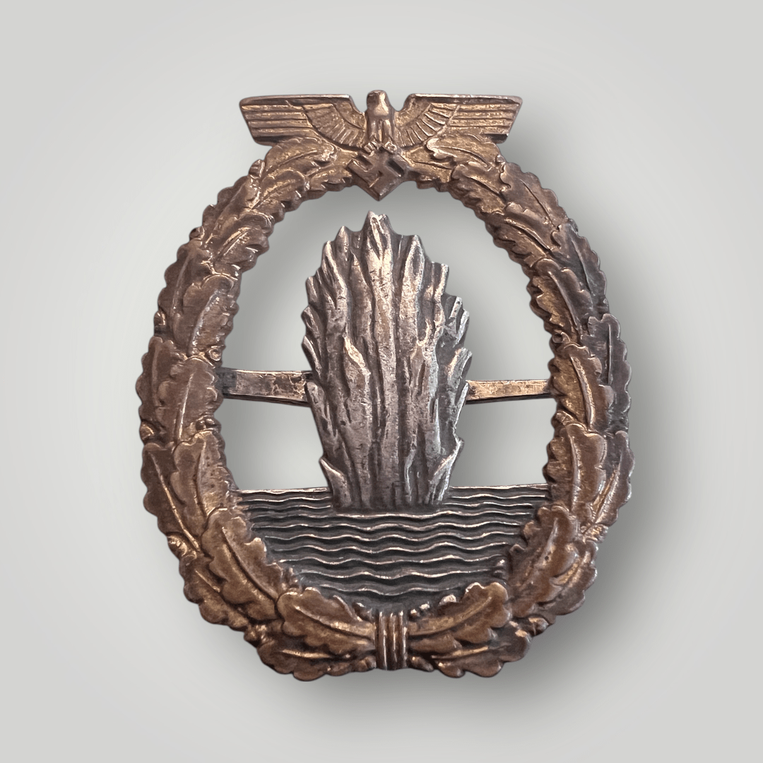 An original German WW2 Kriegsmarine Minesweepers Badge by Wilhelm. The badge is constructed in tombak with a nice patina with nice gilt with nice silver finish.