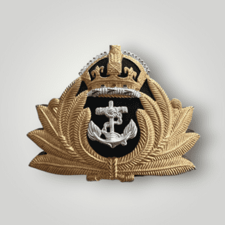 An original British WW2 Royal Navy Officers Cap Badge,  brass and white metal construction. The badge depicts a silver anchor, with a wrapped cable, surrounded by gold laurel leaves surmounted by a padded velvet King's crown, with red, blue, and green stones embedded.