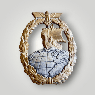 This is an original Kriegsmarine Auxiliary Cruiser Badge by C.E.Juncker. The front features an oval oak leaf wreath with a Kriegsmarine eagle holding a mobile swastika, encircling a central motif of a Viking longship traversing the Northern Hemisphere.