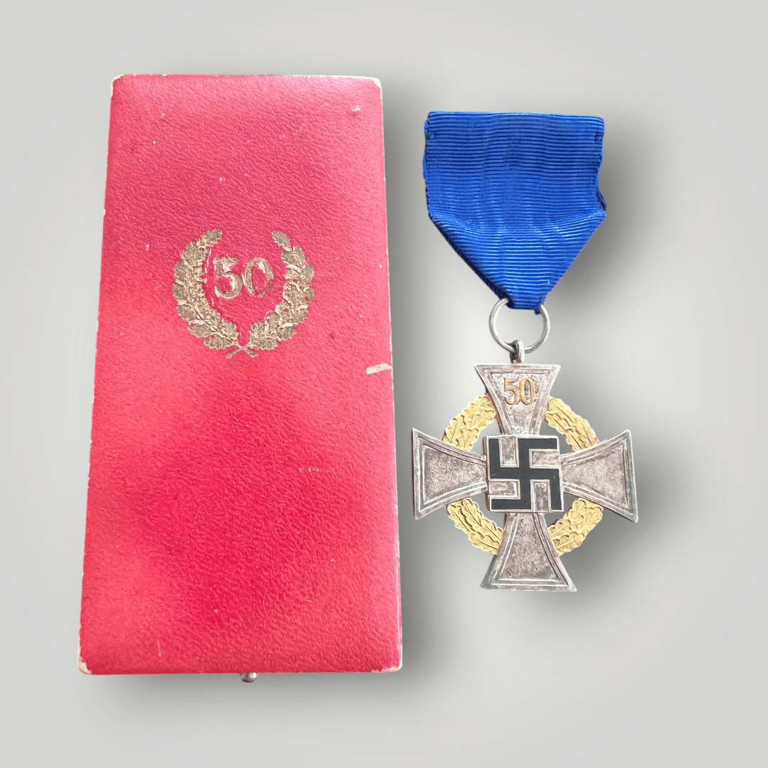 A rare National Faithful Service Medal 50 Years with presentation case, constructed from die-struck nickel silver base with gold-coloured gilt. The medal features a cross pattée with an oak leaf wreath running between the cross’s arms, with a black-enamelled swastika in the centre bearing the number 50 in gold in the top arm.