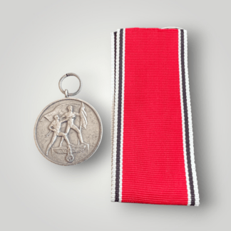 An original Anschluss Medal, constructed in tombac complete with long original ribbon in red, black and white edges. The obverse of the medal depicts a symbolic image of a man holding the Nazi flag on a podium bearing the emblem of the Third Reich, with the second man in broken shackles.