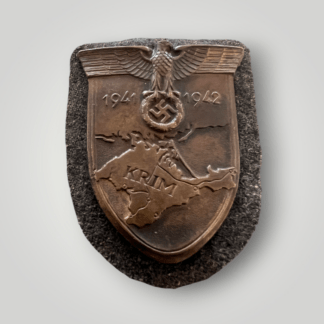 An original Luftwaffe Krim Campaign Shield magnetic version with bronze finish with beautiful patina, mounted on Luftwaffe blue-grey fabric. The reverse of the shield is complete with prongs and papper backing.