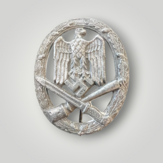 An original General Assault Badge by Assmann, constructed in zinc using a process called liquid-mold casting. The badge features an oval oak leaf wreath with acorns, with a German national eagle facing right, clutching a swastika, positioned above a crossed bayonet and a stick hand grenade.
