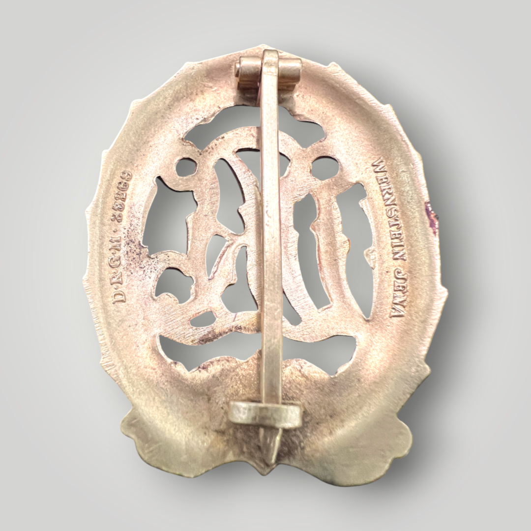 Reverse image of an original German DRL Sports Badge Gold, tombac construction. The obverse consists of "DRL' script superimposed in the centre surrounded by an oak wreath with a swastika and bow below.