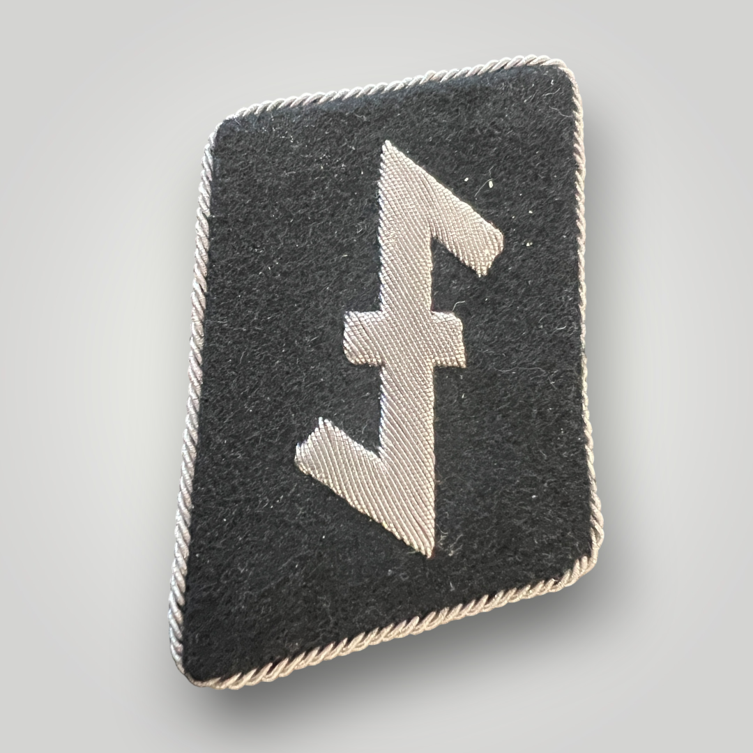 A scarce Waffen-SS 23rd SS Nederland Division officer’s collar tab. The collar tab is hand-embroidered in silver bullion on black doeskin material with silver twisted braid around the edges. The collar tab features a ‘Wolfsangel’ symbol which was believed to ward of wolves in ancient times.