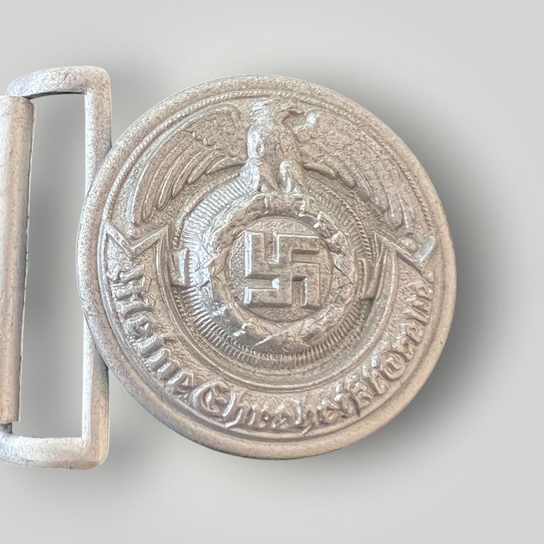 An original Waffen-SS Officer’s Belt Buckle Stamped SS RZM 36/42 OLC, constructed in a zinc. The obverse of the SS officer's belt buckle is round and depicts an eagle with outstretched wings clutching a wreathed swastika in its talons, with a scroll below with the inscription 'Meine Ehre heißt Treue’ (My Honour Is Loyalty).