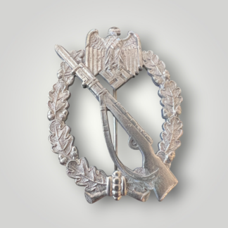 An original German WW2 Infantry Assault Badge by Paul Meybauer, constructed from silver-plated zinc. The obverse features an oval oak-leaf wreath with a diagonally K98 rifle with fixed bayonet and sling, surmounted by a Wehrmacht eagle clutching a canted swastika.