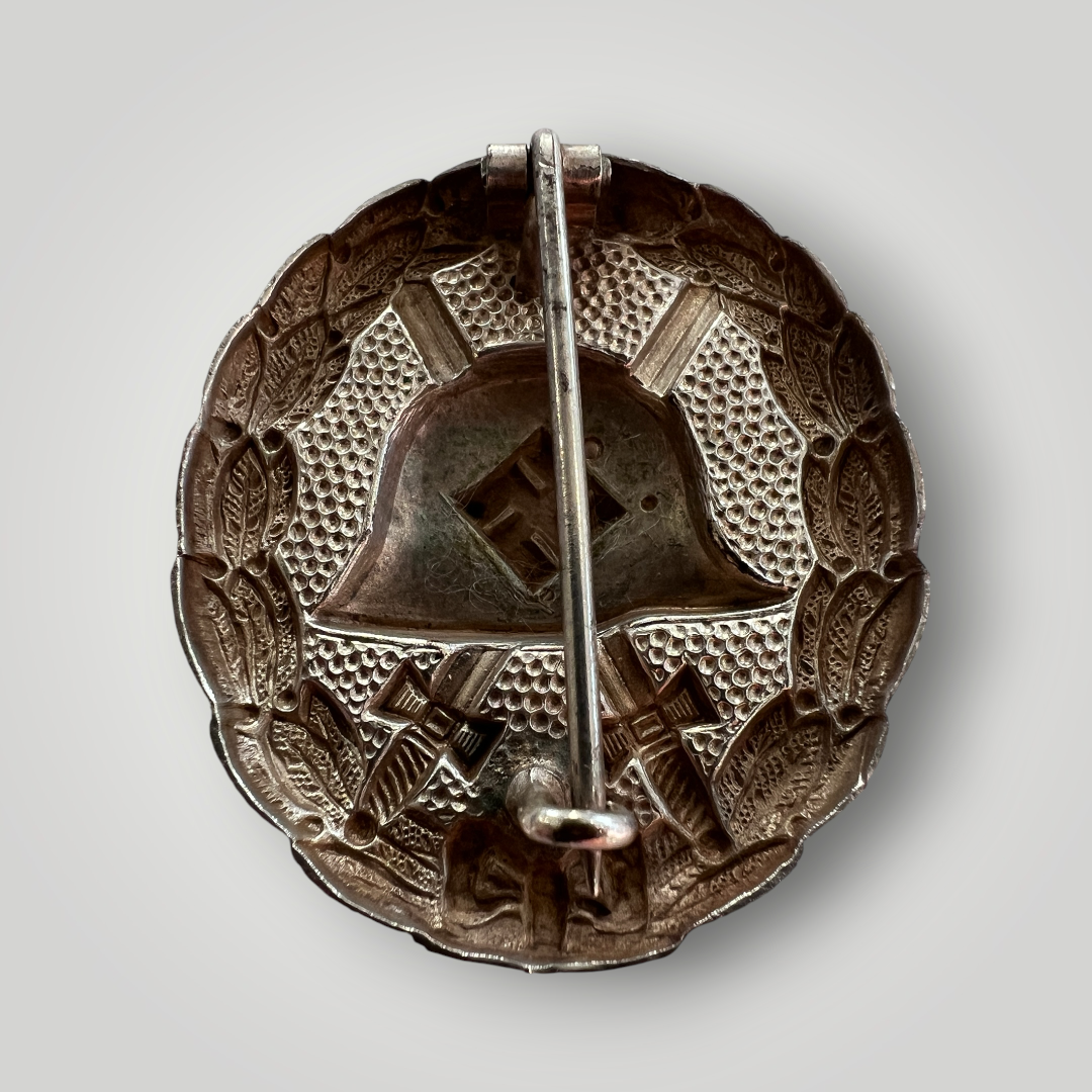 Reverse image of a German WW2 Silver Wound Badge 1st Pattern Legion Condor, die-stamped in tombac with hollow back.